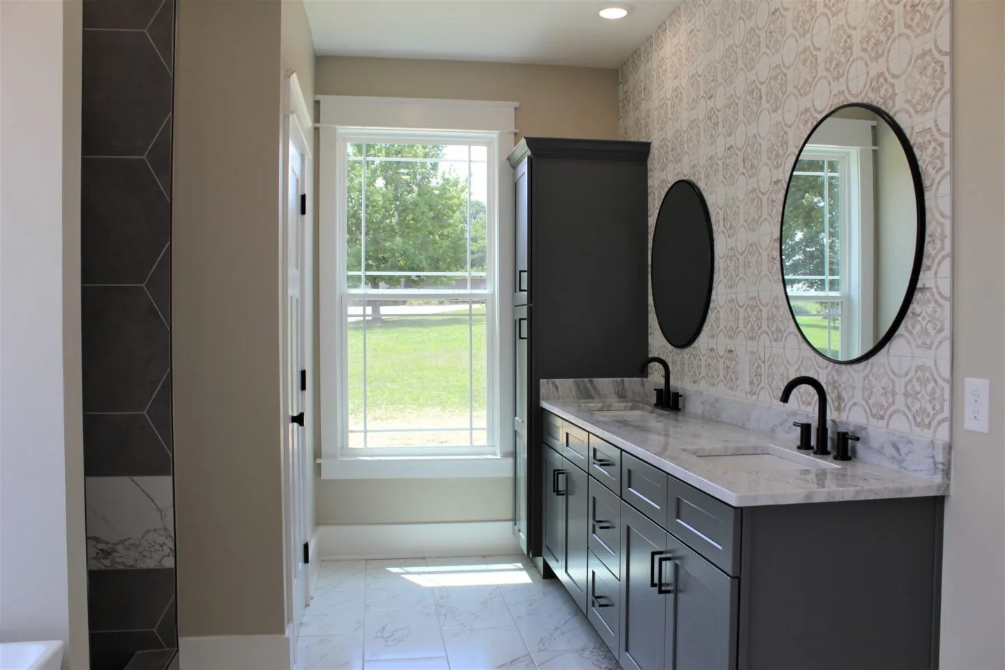 Marble countertop bathroom vanity with dark cabinets and round mirrors