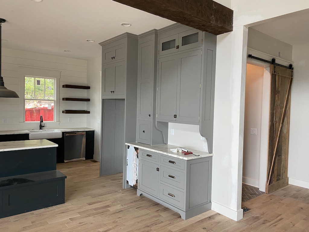 Grey inset custom kitchen cabinetry with reclaimed wood beam