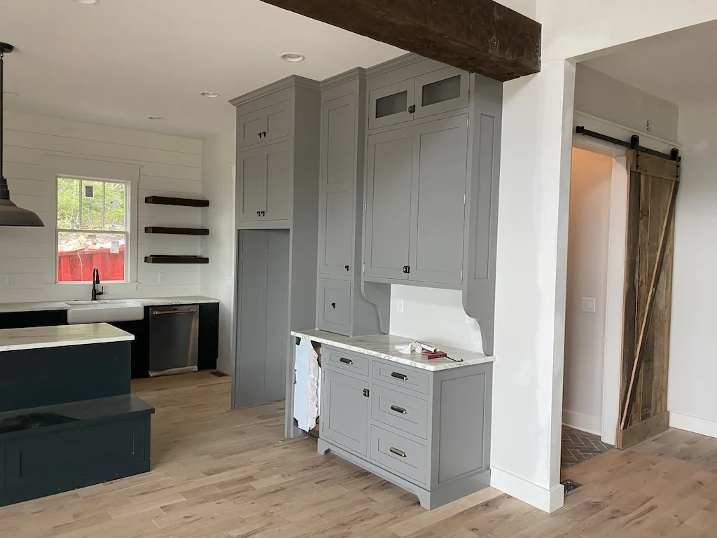 Grey inset custom kitchen cabinetry with reclaimed wood beam