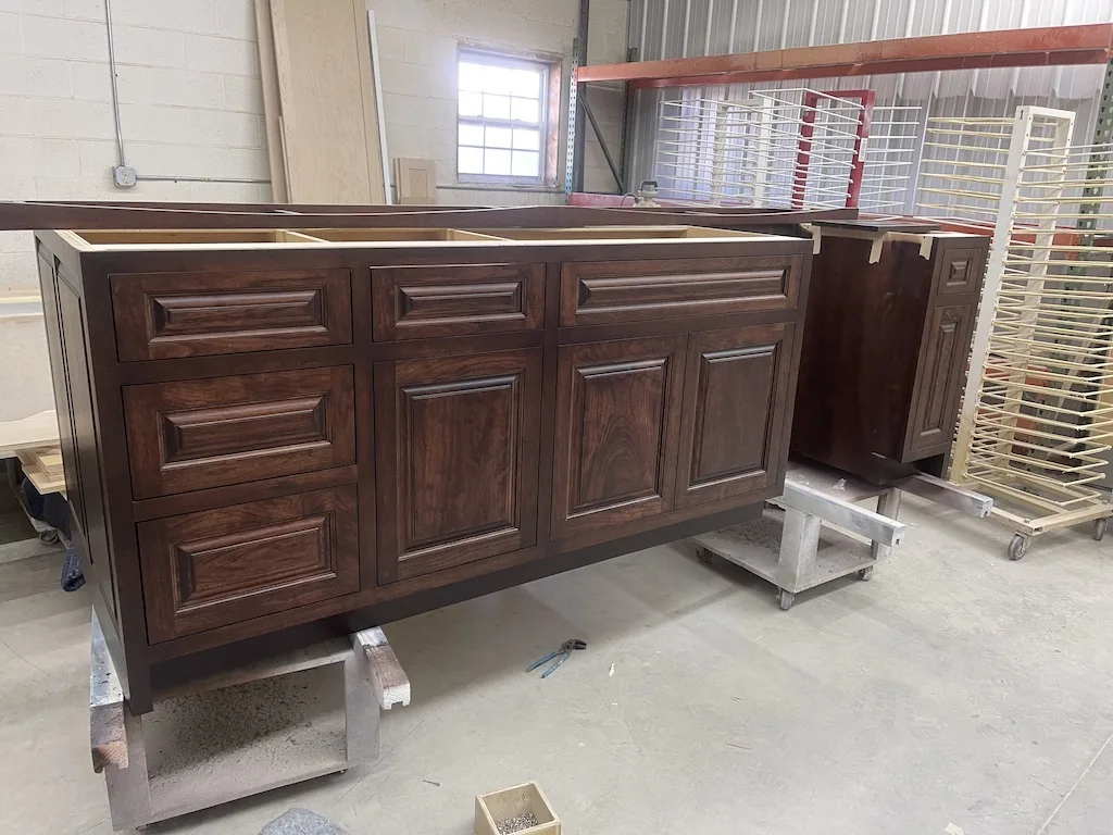 Stained cherry vanity cabinets being finished inside the Holman's shop